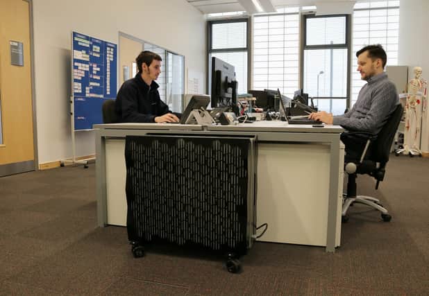 AMRC project engineers Sam Hyde (left) and Valdis Krumins at work next to the portable Iceotope workstation in the AMRC's Design, Prototyping and Testing Centre offices
