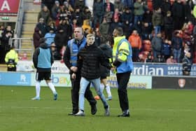 One of the pitch invaders is led away.