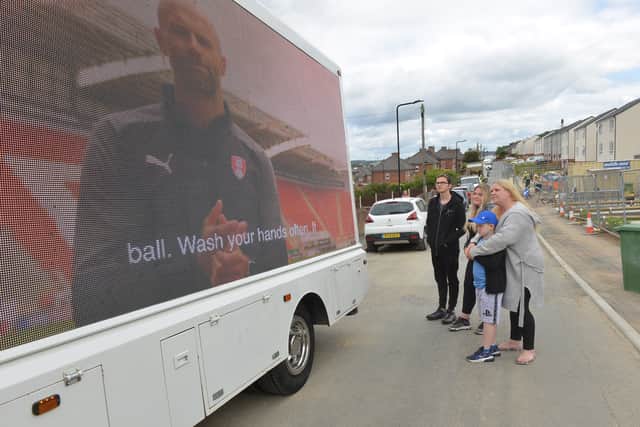 Natalie Robinson and her family watch Millers boss Paul Warne's key Covid-19 message on screen as the truck tours Rotherham this week.
