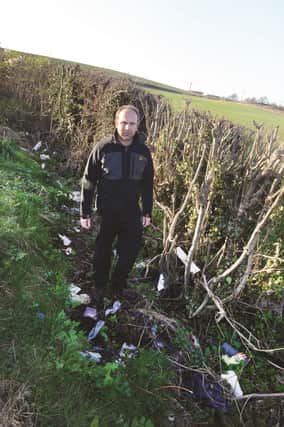 Parish council vice chairman Eddie Herbert with some of the fly tipping on Holmes Lane at Hooton Roberts.