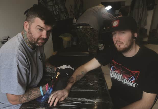 Kieran's dad Chris MacFarlane (left) is seen tattooing one of the charity designs on to client Shaun Tweedale. 171764-2