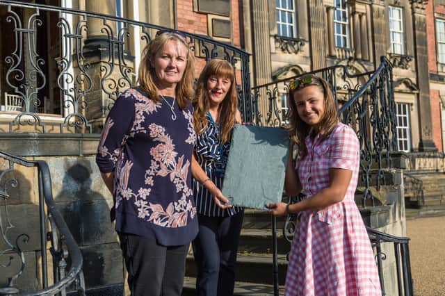 
Left to right: Sarah McLeod, chief executive of Wentworth Woodhouse Preservation Trust, presents a “thank you” sponsored roof slate to volunteers Lisa Guy and Tilly Poskitt.