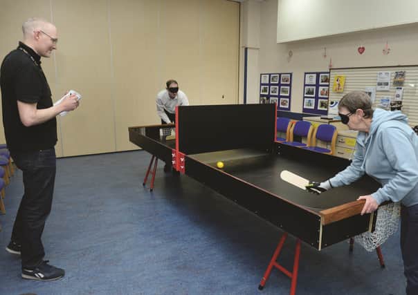 Advertiser reporter Gareth Dennison has a go at playing Showdown with service user Lindsey Green, under the watchful eye of activities and fundraising support offer Ben Gilder.