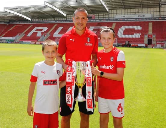 Richard Wood shows off the League One runners-up trophy at AESSEAL New York Stadium with sons Jenson and Graye. The skipper was allowed to take the trophy home for the Millers' online promotion party before returning it the next day