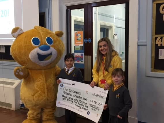 Caitlin Hallatt and Theo the Bear of Sheffield Children's Hospital receiving a cheque from Eshani Thorpe-Gurung and Eliza Briggs at Listerdale