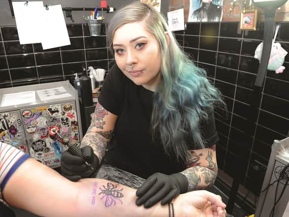 Rotherham tattoo artist Emily Dawson, owner of Holy Ghost Tattoos, is seen tattooing the Manchester Bee on a client. Emily will be travelling to Manchester to tattoo clients, with money raised going to the appeal. 170875-3
