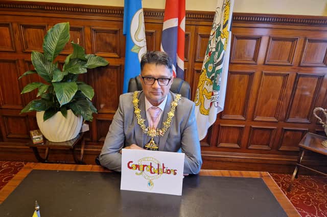 The Mayor with his card which is on display in his office 