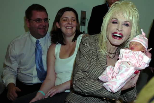 Dolly Parton meets baby Emma Jarman at Rotherham Hospital as her parents Shane and Claire look on. Dolly was in Rotherham to launch a reading scheme.