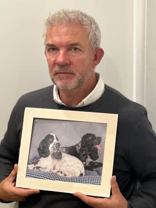 Philip holding a picture of cocker spaniels Bella (left) and Lilly